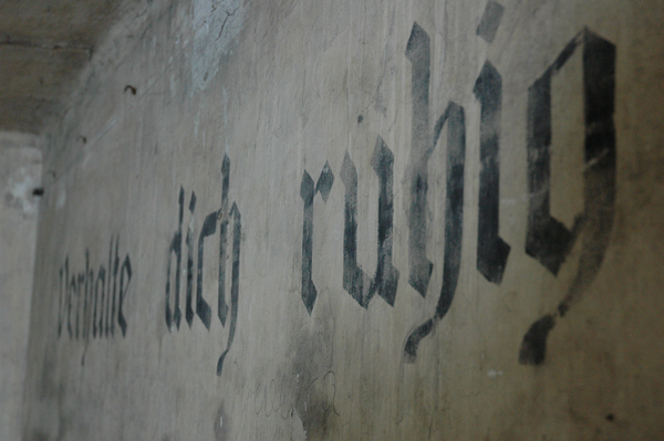 Schriftzug „Verhalte dich ruhig“ in einer Baracke im KZ Auschwitz