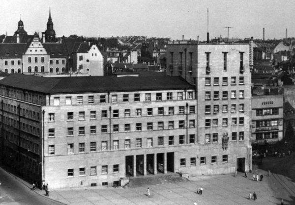 Ratshof Schwarz-Weiß-Foto des Ratshofs in Halle/Saale. Ein fünfstöckiges Gebäude an einem großen Platz. An der Ecke erhebt sich ein Turm. Der Eingangsbereich ist als fünfteiliges Tor gestaltet.